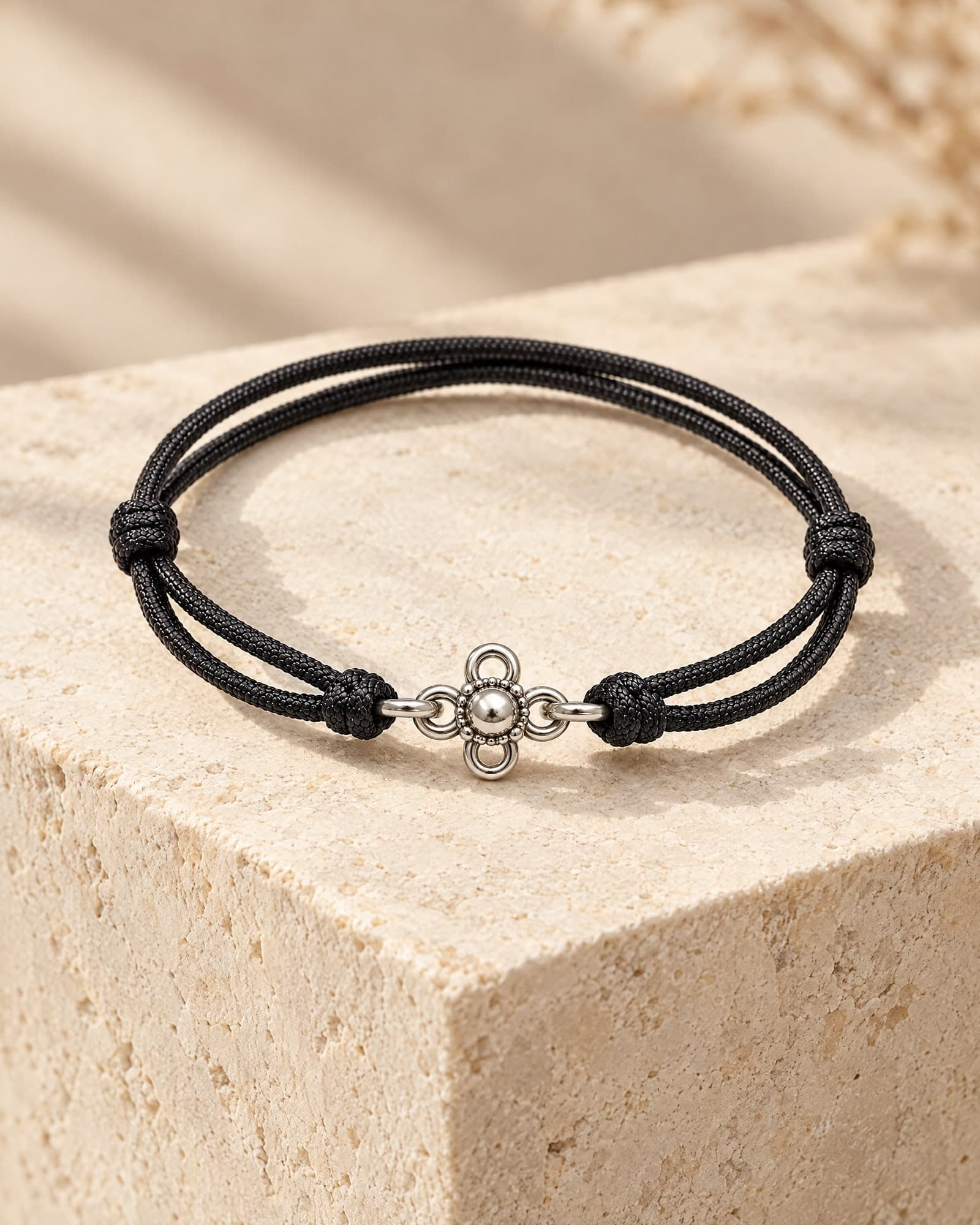 The Lotus in black cord, resting on pale limestone